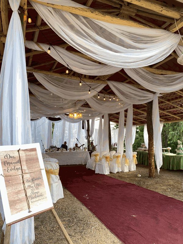 Recepción de boda con techo drapeado en tela blanca y alfombra roja