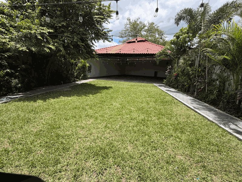 Jardín para eventos con grama, luces colgantes y área techada